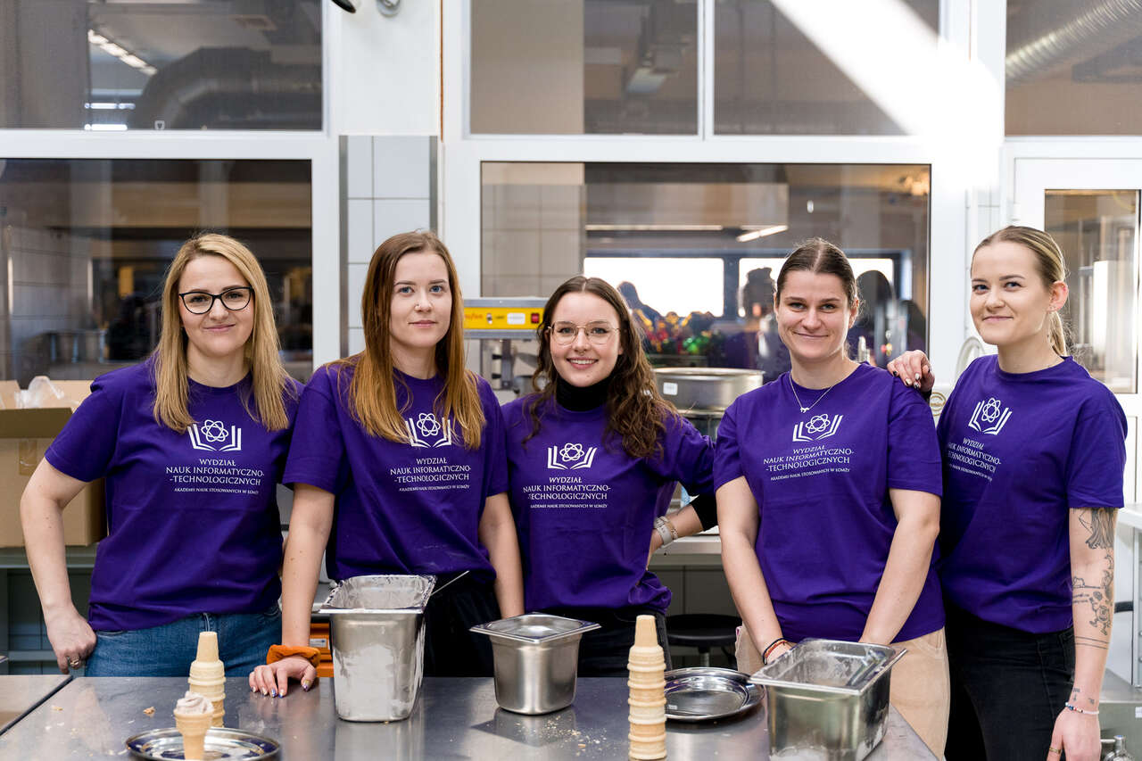 Pięć kobiet ubranych w fioletowe koszulki z logo Wydziału Nauk Informatyczno-Technologicznych.