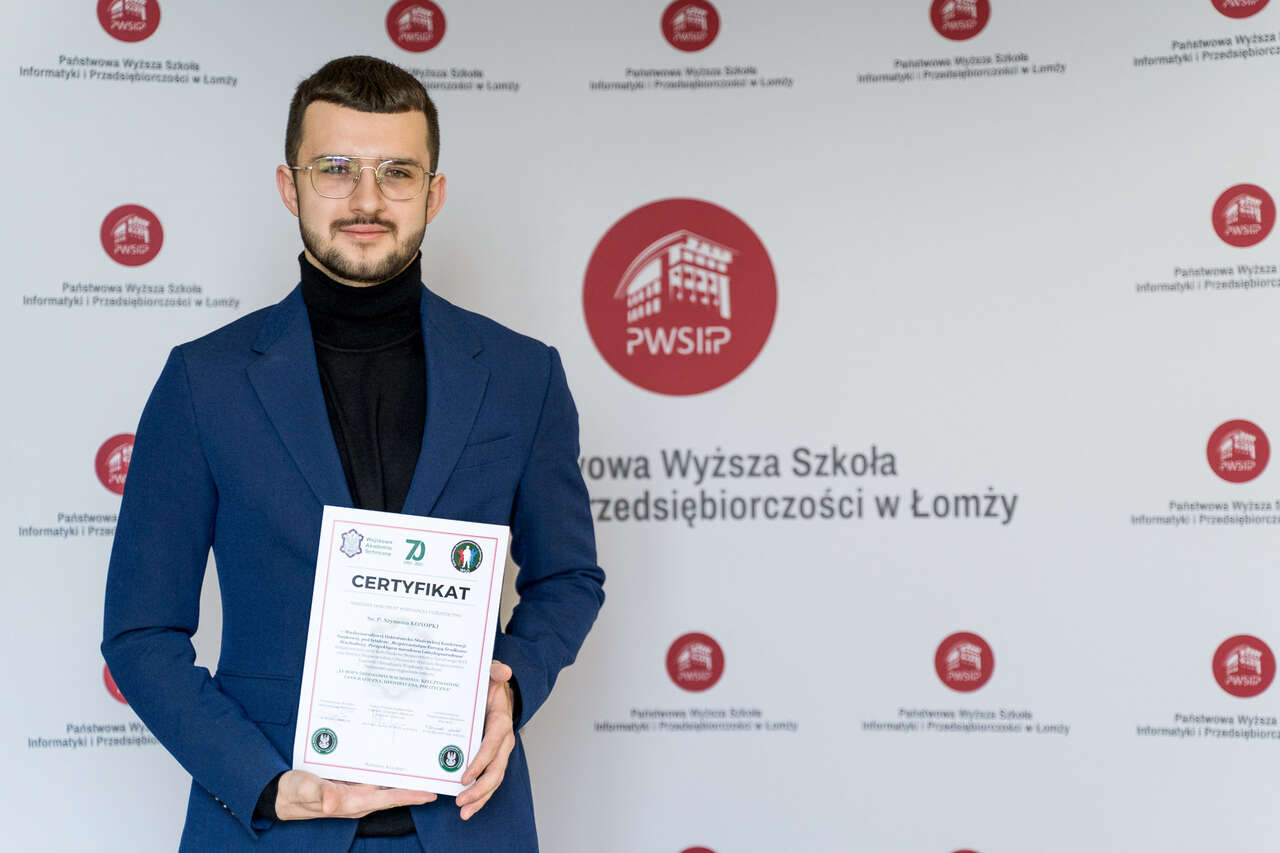 Szymon Konopka trzyma certyfikat w dłoniach